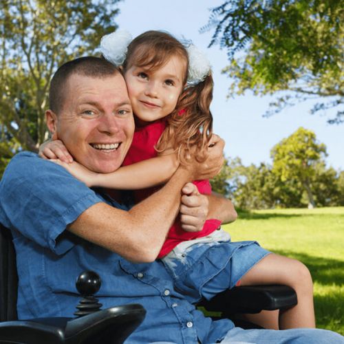 ein im Rollstuhl sitzender Mann mit seiner Tochter