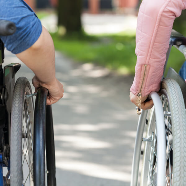 zwei nebeneinander stehende Rollstuhfahrer