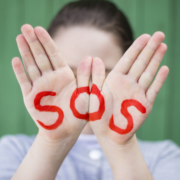 Kinderhände mit Schriftzug SOS