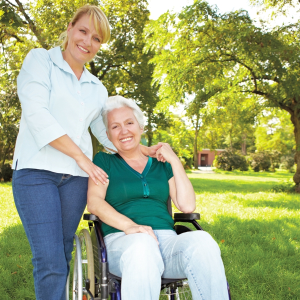 zwei Frauen im Garten, eine Frau sitzt im Rollstuhl